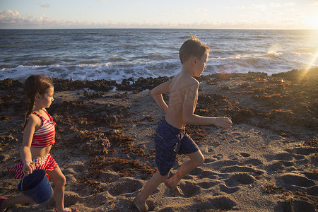 男孩和妹妹在海滩上跑步美国佛罗里达州朱庇特岛吹石保护区