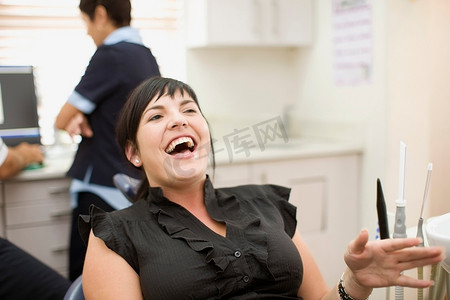 中年女性大笑摄影照片_牙医办公室里的女人大笑