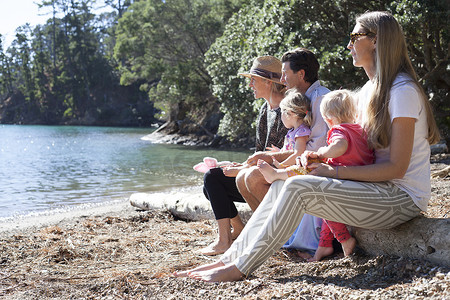 家人朋友坐在新西兰海滩的树干上