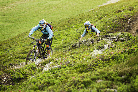 年轻的男女山地自行车手在山坡上骑自行车