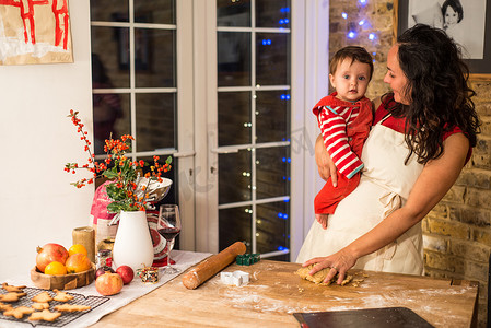 成熟的女人在厨房柜台前带着小儿子准备圣诞饼干