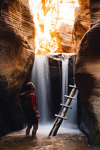 美国犹他州卡纳拉维尔瀑布边砂岩洞穴中的徒步旅行者