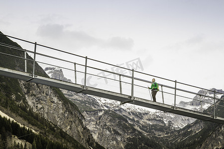 在奥地利蒂罗尔霍尔兹高的人行桥上徒步旅行的年轻女子的低角度视角