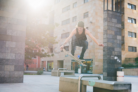 年轻男子滑板运动员跳过城市广场座位
