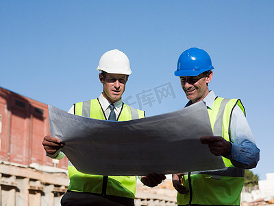 成熟的男人在建筑工地上检查蓝图