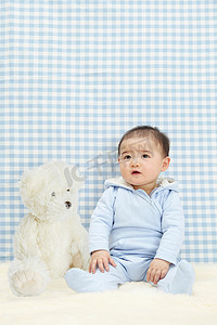 墙纸蓝摄影照片_男婴抱着柔软的玩具坐着