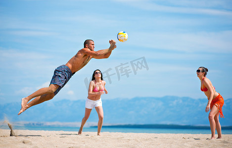理头发摄影照片_在海滩上打排球的朋友