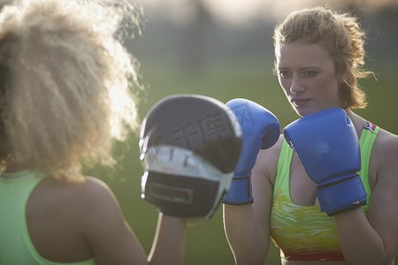 两名戴着拳击手套的女子在公园里锻炼