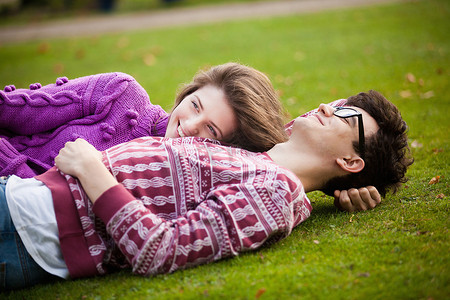 一对十几岁的情侣躺在公园的草地上