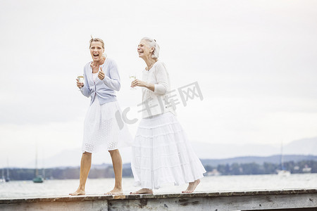 两个女性朋友沿着码头走着笑着