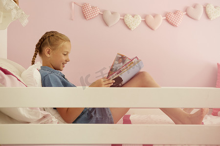 女孩坐在床上阅读杂志的侧视
