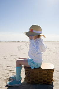 坐在海滩野餐篮上的女孩