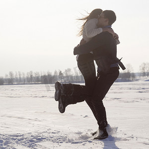 年轻男子在白雪覆盖的田野上背着女子