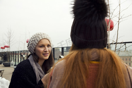 成年女子摄影照片_两名年轻的成年女子在屋顶露台上聊天