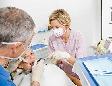 公司文化牌摄影照片_为病人服务的牙医和助理
