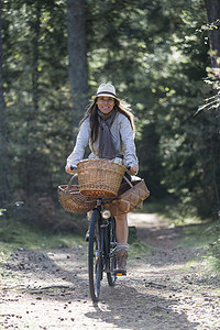 三叶草摄影照片_带着觅食篮子在林间小路上骑车的成年女子