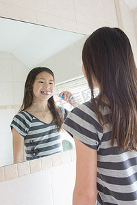 在浴室镜子前刷牙的女孩