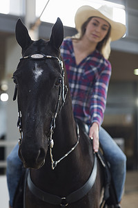 年轻女子骑马运动员在室内围场拍马