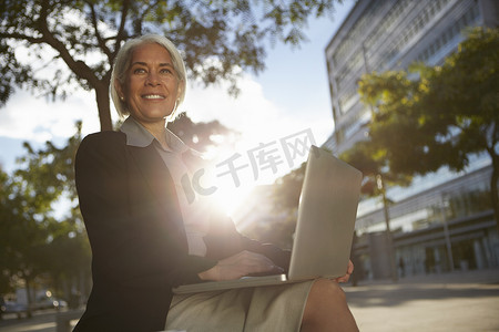 商务沟通技巧摄影照片_女商人坐在外面用笔记本电脑