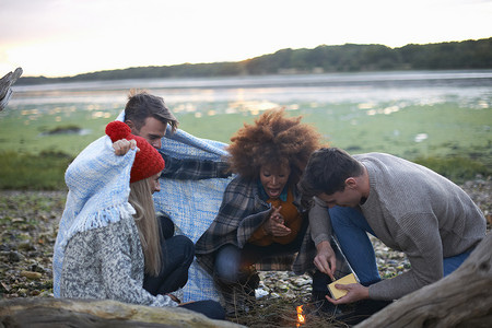 四个成年朋友在海滩上点燃篝火