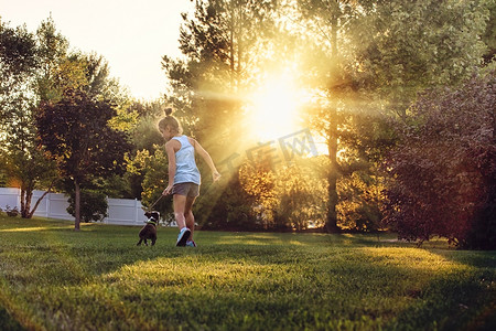 动物与动物宝宝摄影照片_公园里的女孩和波士顿梗犬小狗奔跑的背影
