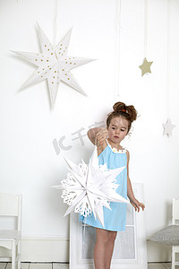 挂灯笼剪纸摄影照片_剪纸的女孩星星衬托着白色的墙墙上挂着星星