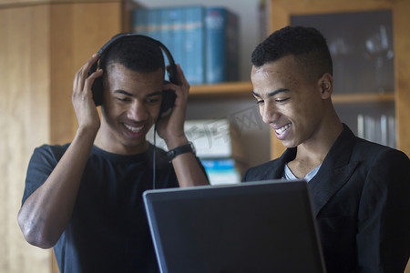 家里的双胞胎兄弟看着笔记本电脑戴着耳机微笑着
