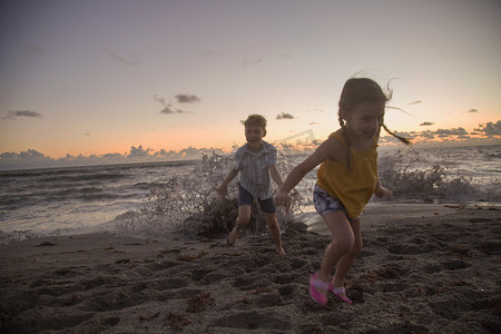 美国佛罗里达州朱庇特岛男孩和妹妹在日出时逃离溅起的海浪吹石保护区
