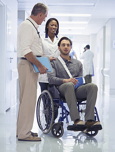 医生向坐在轮椅上的男子咨询并打着吊带