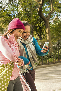 一对双胞胎在公园里散步和使用智能手机