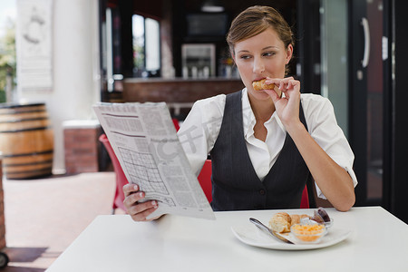 在餐厅看报纸摄影照片_吃早餐的女商人
