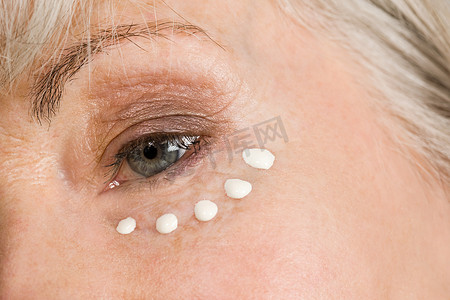皮肤老化摄影照片_涂眼霜的女人