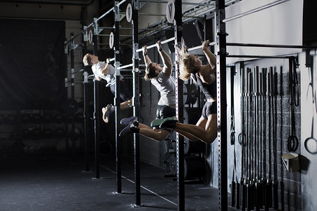 三个年轻人在健身房的墙上酒吧里训练