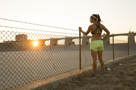 美国加利福尼亚州范奈斯日落时分女运动员在铁丝网旁做白日梦