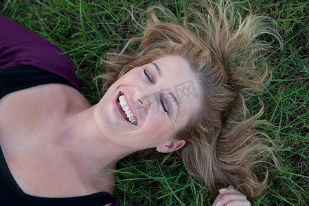 闭着眼睛摄影照片_微笑的女人躺在草地上
