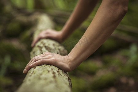 中年妇女在森林里锻炼在原木上做俯卧撑特写