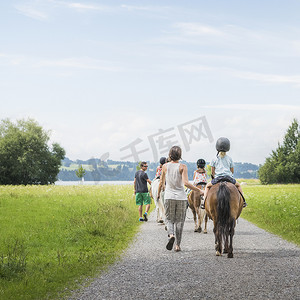 德国巴伐利亚州富森父母引导孩子骑马的背影