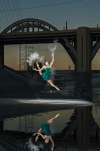 日落时分美国洛杉矶女芭蕾舞演员在河面上跳跃着释放火药爆炸