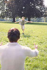 一个男孩在公园里跑向他的父亲