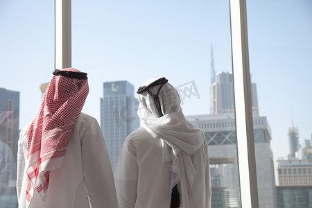 中东商人透过办公室窗口看迪拜