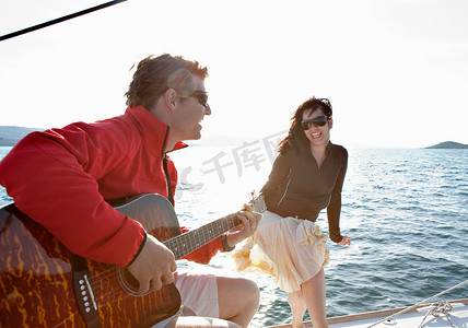 游艇上弹吉他的女人和男人