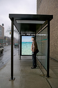 怀旧海报摄影照片_一名男子站在巴士候车处