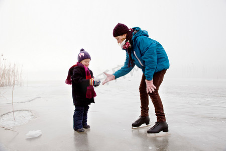 曲线面摄影照片_女孩和男孩在结冰的湖面上滑冰