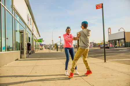 美国布鲁克林十几岁的男孩和女孩在人行道上牵着手旋转