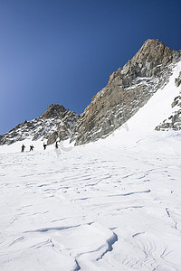 四名男性滑雪板运动员徒步攀登瑞士阿尔卑斯山特里恩特积雪覆盖的风景
