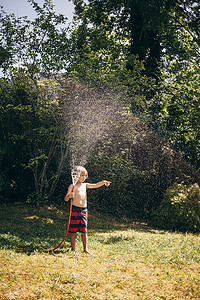全景男孩在花园里拿着喷水软管看着别处指着布卢登茨奥地利