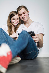 一对十几岁的夫妇看着数字平板电脑共用耳机