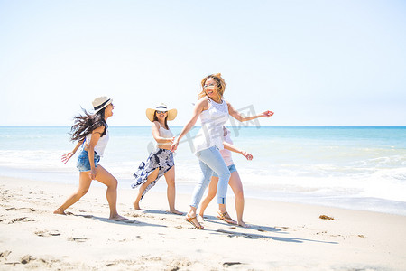 四个成年女性朋友在美国加利福尼亚州马里布的海滩上嬉戏