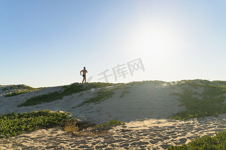 一位年轻人在沙丘上奔跑