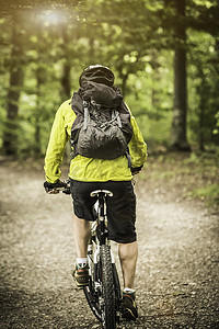 成年男性山地自行车手在森林中骑行的后视线